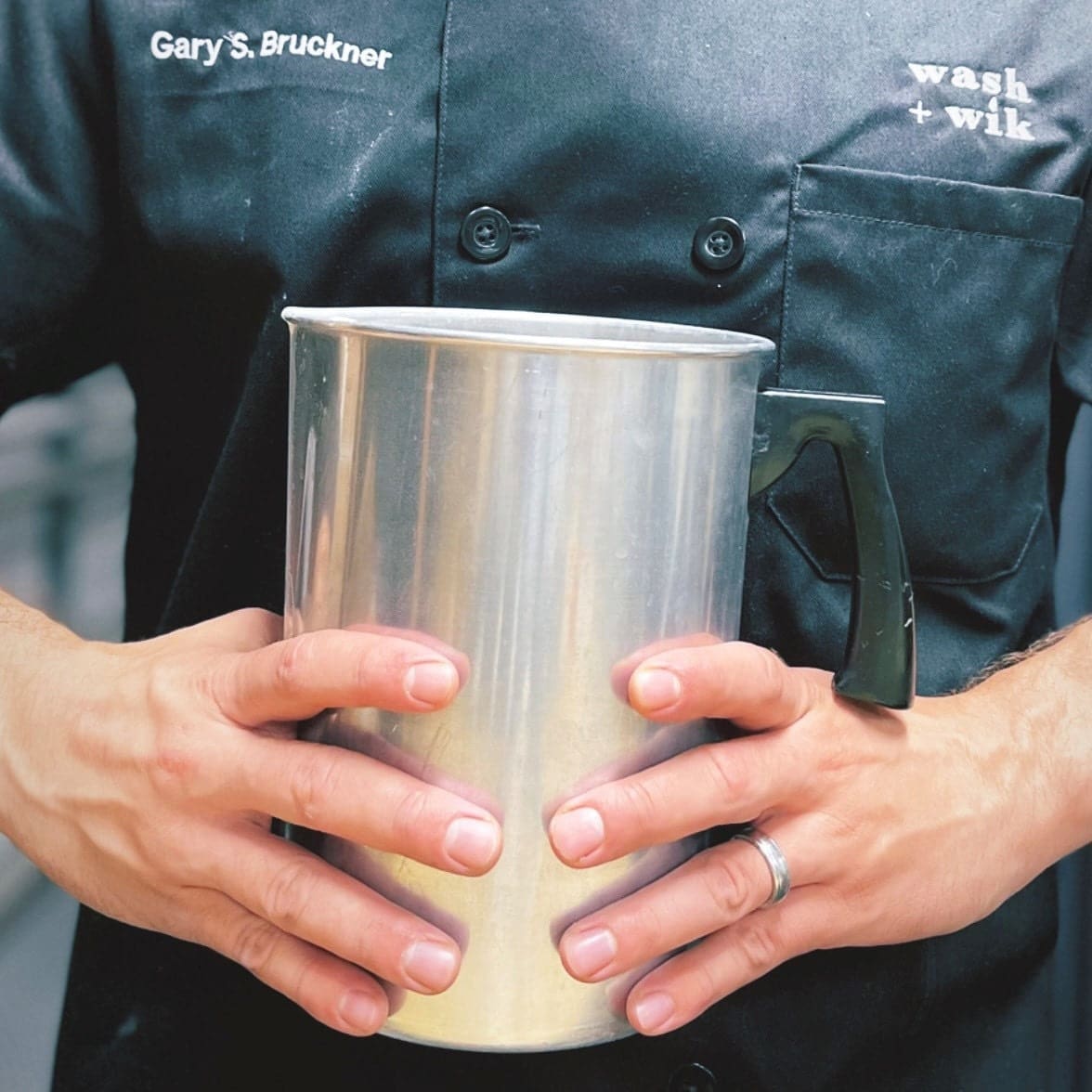 A person holding a metal cup in their hands.